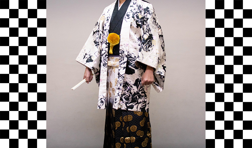男性袴コレクション10。羽織が白地で豪華な黒い柄と着物が黒、袴が白黒ぼかしの亀甲柄のコーデ